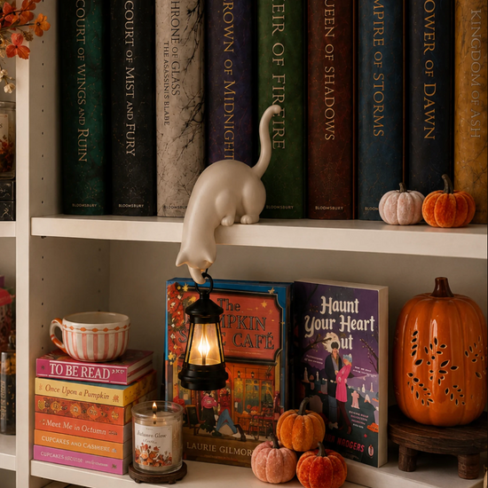 White cat shelf lantern beside books and autumn decorations